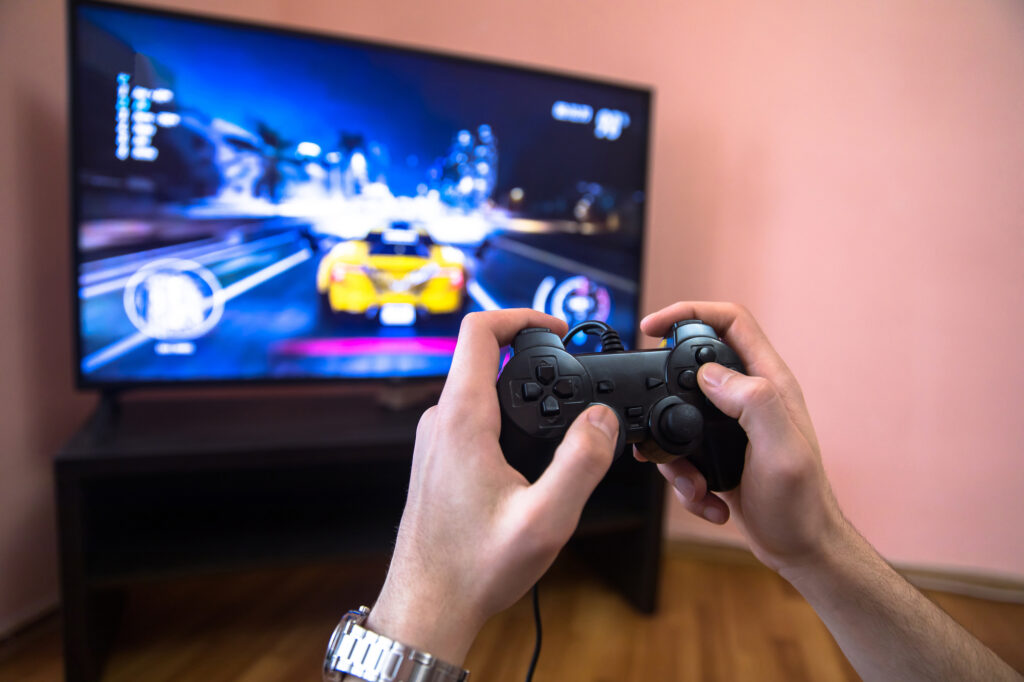 A person engrossed in a video game in front of a television, exploring how to make money off Steam.