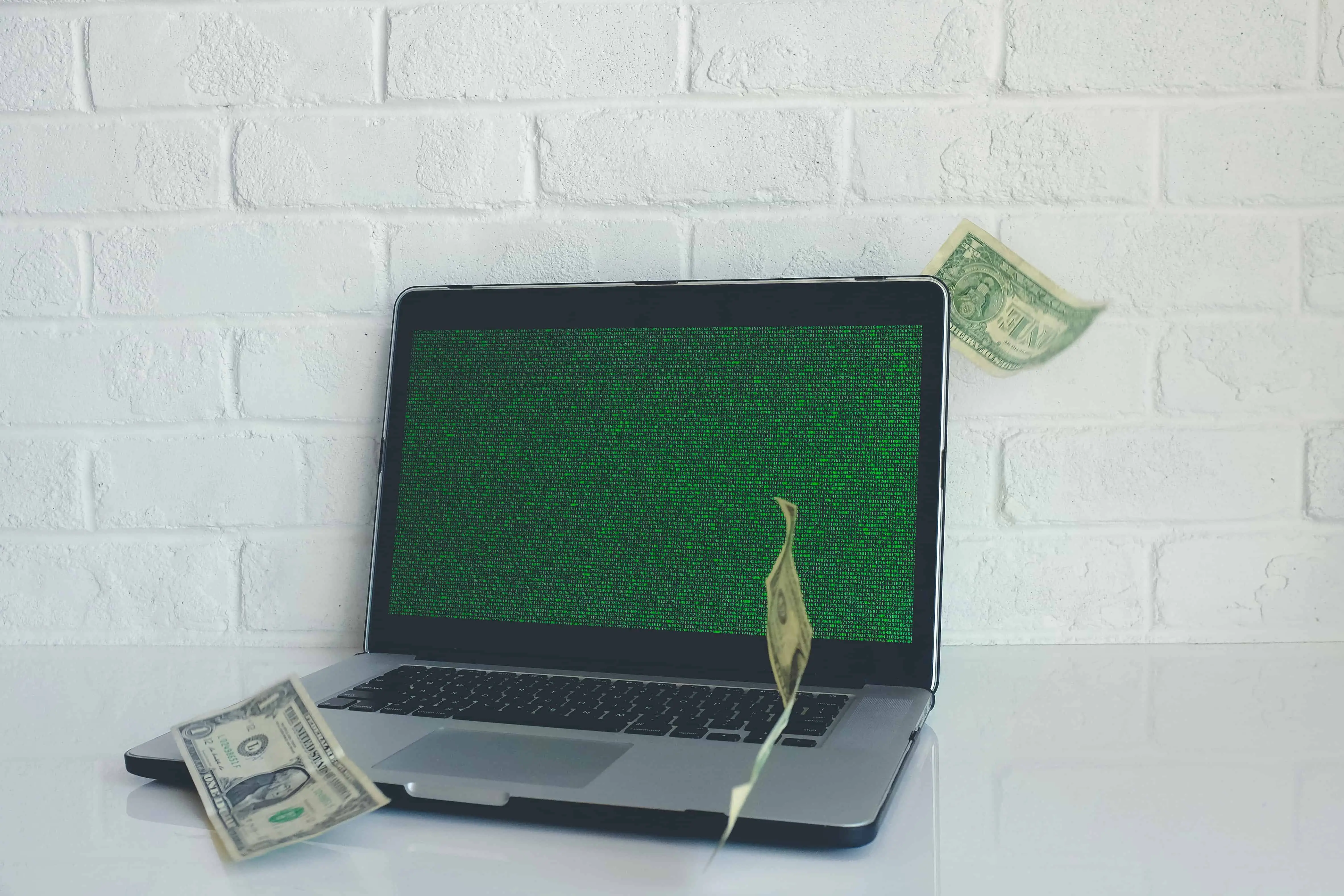 a laptop with dollar bills money floating around - sell t shirts to make money online!